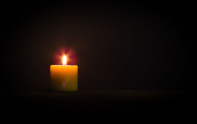 Close-up of illuminated candle in darkroom