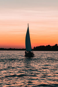 Sailboat sailing on sea against sky during sunset