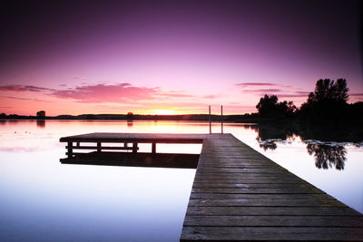 Pier over lake against sky during sunset