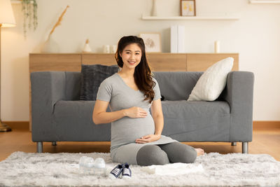 Portrait of smiling young woman sitting on sofa at home