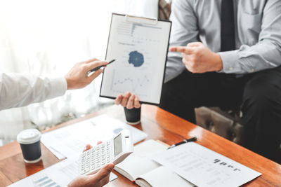 Midsection of business people working on table