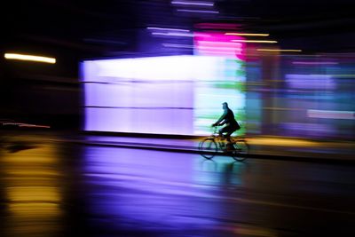 Blurred motion of man cycling at illuminated city