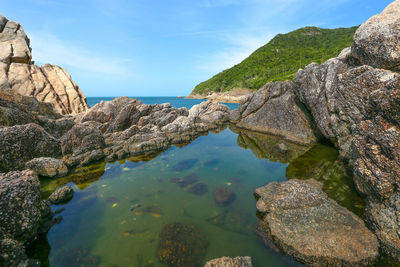 Rock formations by sea against blue sky