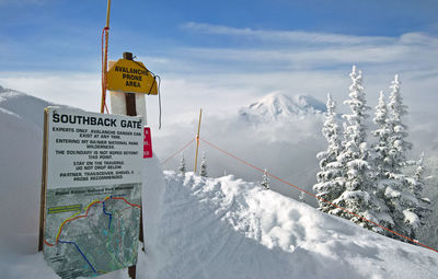 Information sign on snowcapped mountain against sky