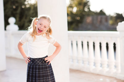 Portrait of cute girl standing against column