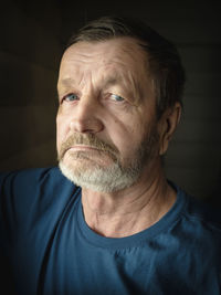 Close-up portrait of senior man against gray background