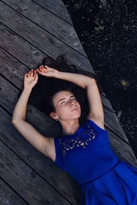 High angle view of woman sleeping on pier by lake