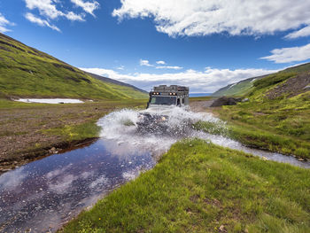 Off-road car crossing river on way to drangajokull glacier