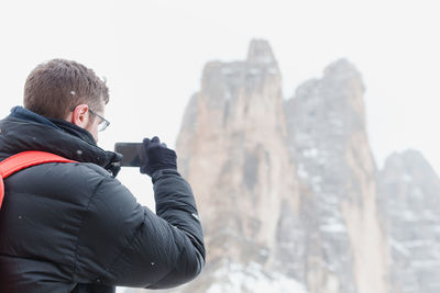 Man on snow covered mountain against sky