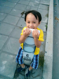 High angle portrait playful of boy with bollard on sidewalk