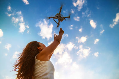 Low angle view of woman with arms raised against sky