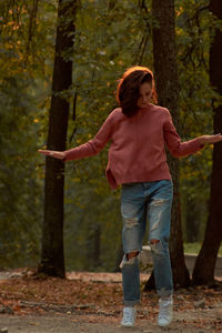 Full length of young woman standing in forest