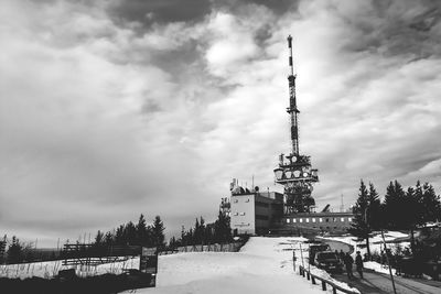 Low angle view of communications tower against cloudy sky on sunny day