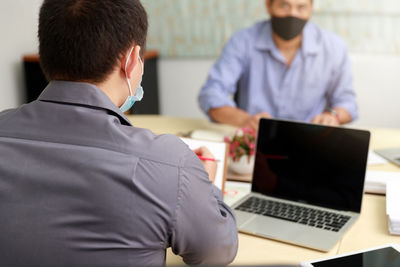 Rear view of man using laptop