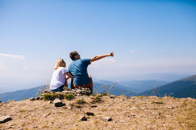 Rear view of people looking at mountain against sky