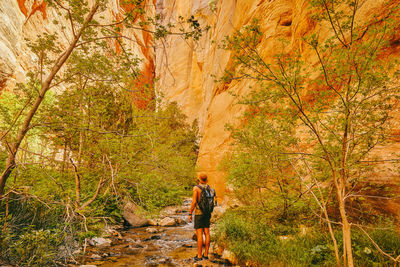 Young man wearing a hat, exploring a slot canyon in kanarra fall, utah