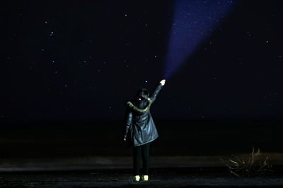 Woman standing against sky at night