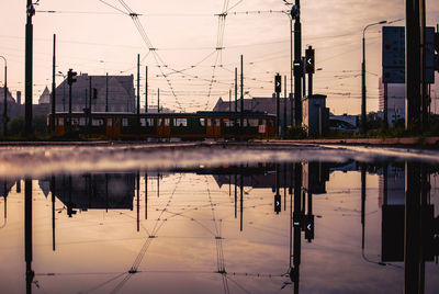 Reflection of electricity pylon in city against sky