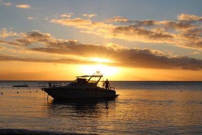 Boat in sea against sky during sunset