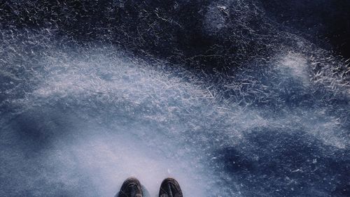 Low section of person standing on frozen lake