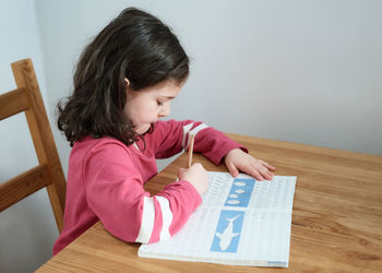 Young girl practicing her writing at the table