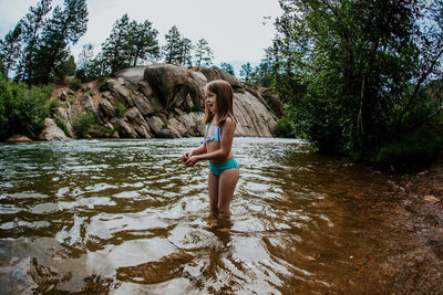 Young girl playing in river wearing a bathing suit