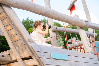 Low angle view of young woman sitting on railing