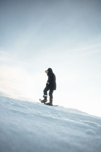 Low angle view of woman hiking in snow against sky