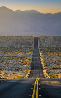 Road leading towards mountain against sky