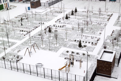 Top view of empty playground and winter park paths are covered with snow