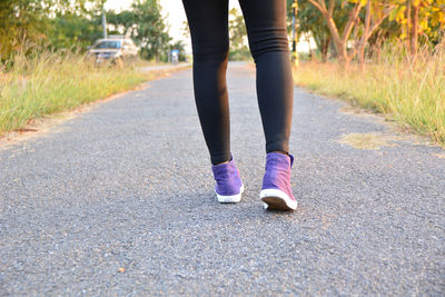 Low section of woman walking on road