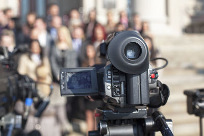 Close-up of television camera against people