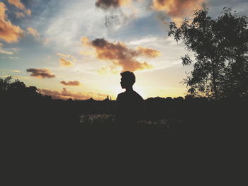 Silhouette man standing by tree against sky during sunset