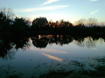 Reflection of trees in water at sunset