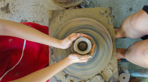Midsection of woman molding shape on pottery wheel