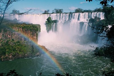 Panoramic view of waterfall by trees against sky