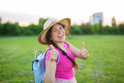 Portrait of smiling woman standing against grass