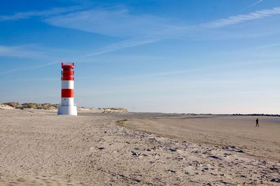 Lighthouse on beach against sky