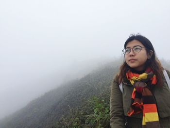 Portrait of smiling young woman in fog against sky