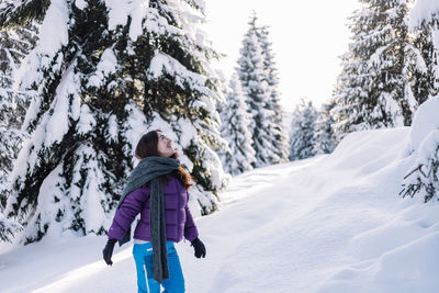 Woman having fun while hiking in the snow during winter, at sunset time.