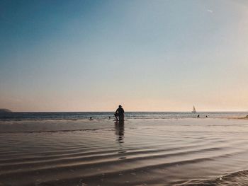 People on beach against clear sky