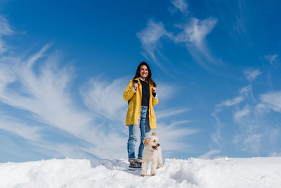 Woman with dog on snow against sky