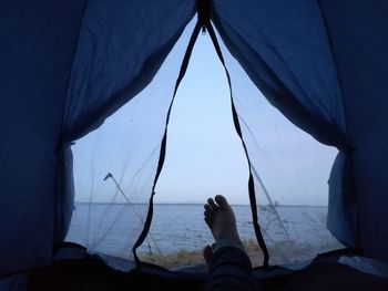 Low section of person on sea against sky