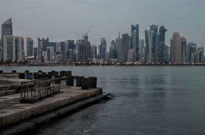 Sea by modern buildings against sky in city