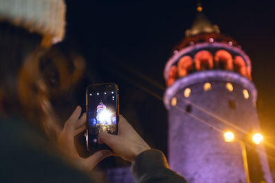 Man photographing illuminated smart phone at night