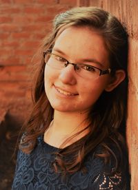 Headshot of a girl in a blue dress while leaning against a wall