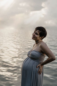 Young woman looking away while standing in sea