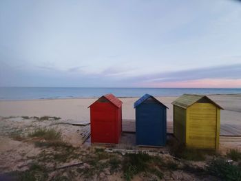 Beach hut by sea against sky