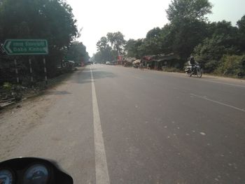 Road amidst trees and city against sky