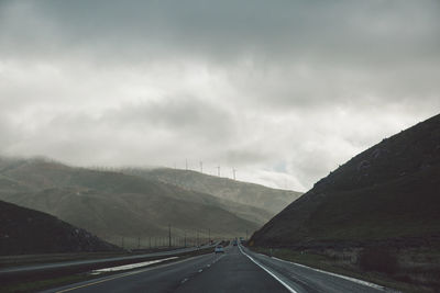 Road by mountains against sky